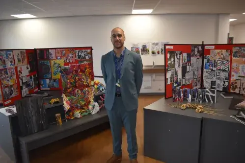 Teacher standing next to art pieces
